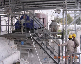 Calcium Carbonate slurry dewatering centrifuge system with hard hat workers looking on